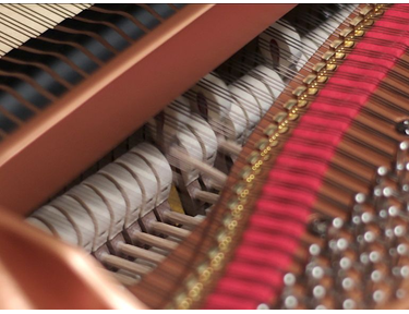 Photograph of a grand piano hammer striking strings