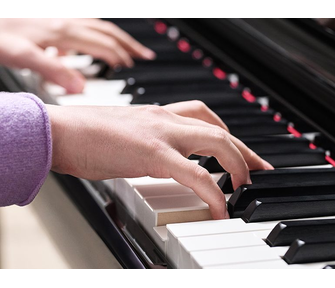 Close-up of a person's hand playing the Yamaha Clavinova CLP-875PE