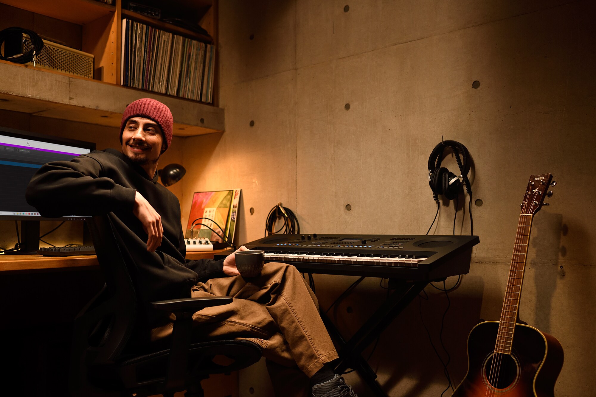 Domácí hudební pracoviště s počítačem a keyboardem, na kterém pracuje klávesista ve svém domácím studiu