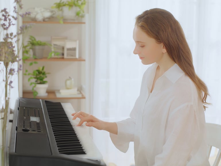 Woman playing the YPT-W320 with one hand.