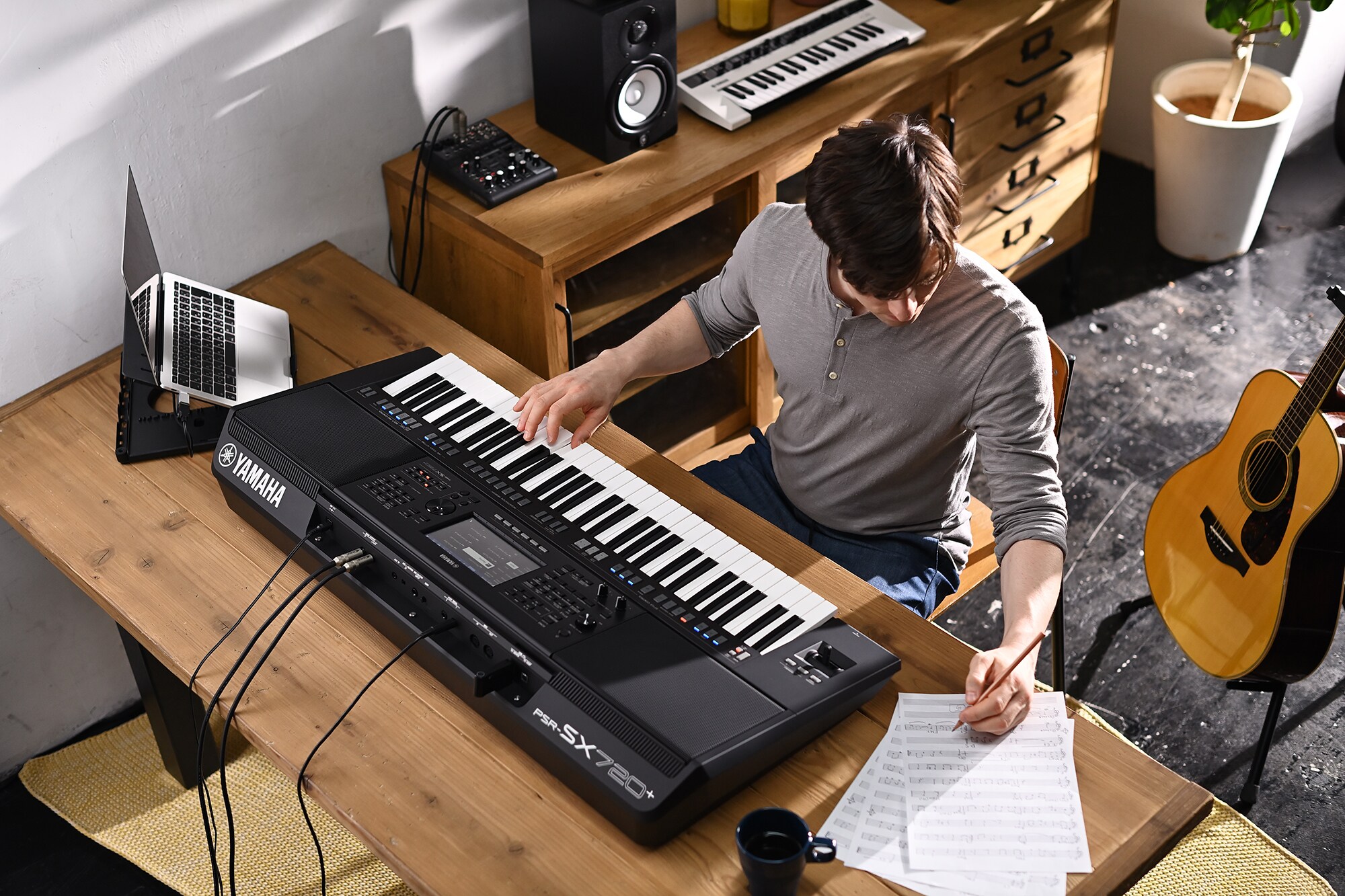 Fotografie osoby, která píše do notového zápisu při hře na aranžovací pracovní stanici Yamaha PSR-SX720+