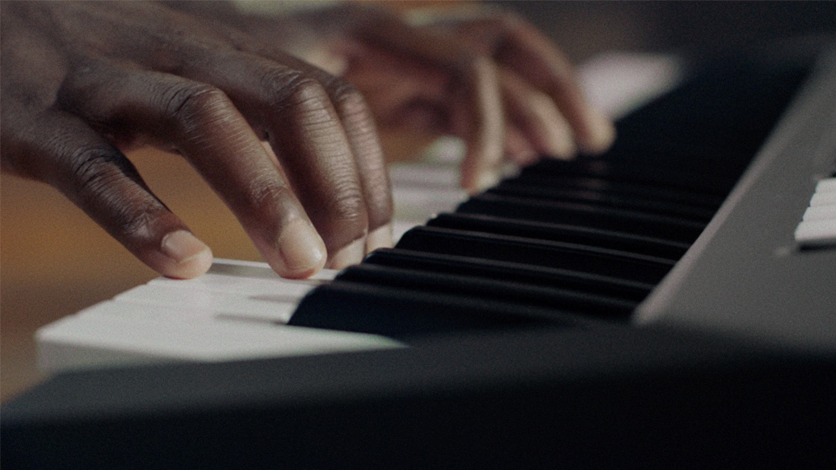 Osoba hrající na keyboard PSR-E483