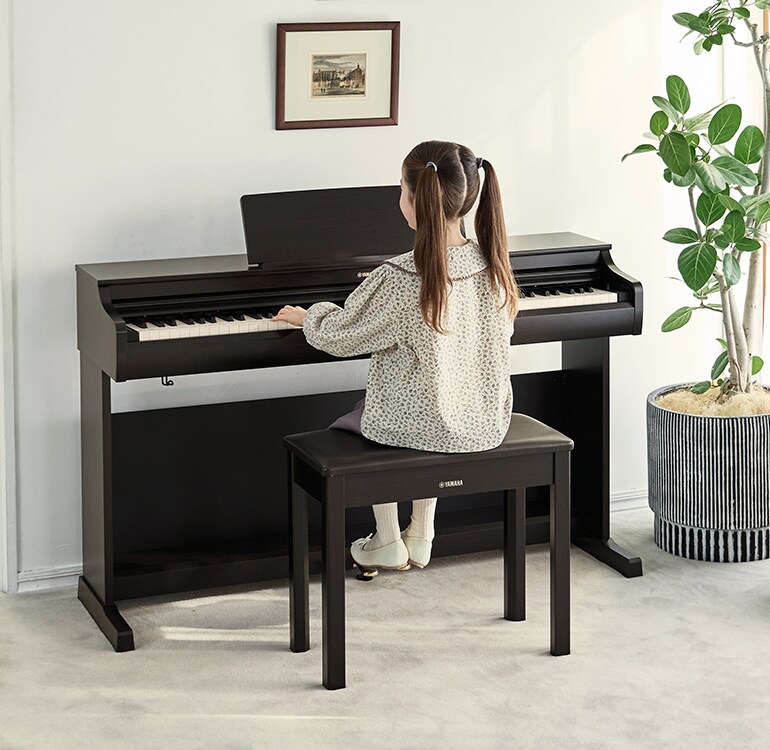 Mladá dívka cvičí na piano ARIUS v obývacím pokoji