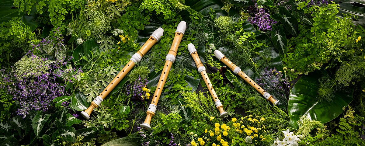 Four Yamaha recorders made of bioplastic placed on a bed of plants.